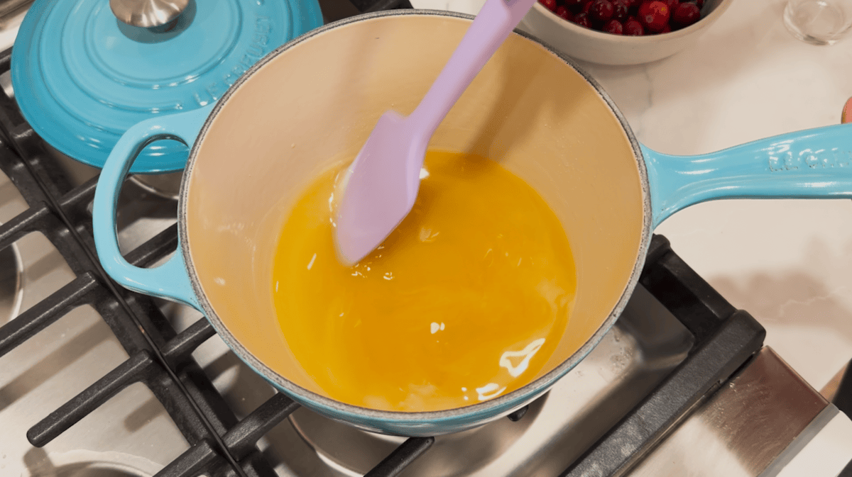 Overhead view of sugar, orange juice, and water in a saucepan.