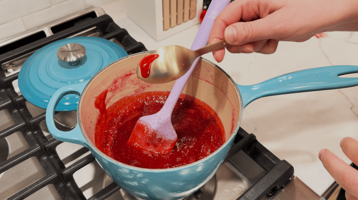 Overhead view of cranberry sauce being stirred on the stovetop.