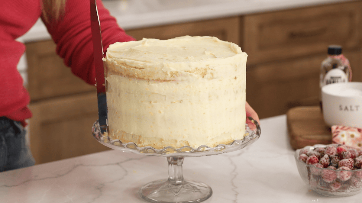 Smoothing an orange infused cream cheese frosting naked-style over a cake.
