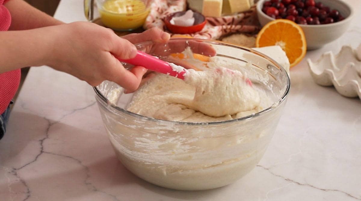 Folding whipped egg whites into cake batter with a spatula.