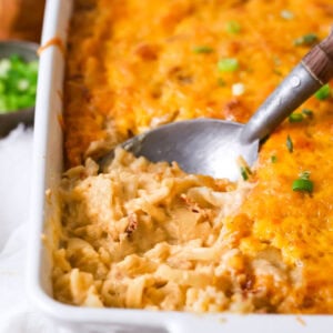 Spoon scooping a serving of hashbrown casserole out of a dish.