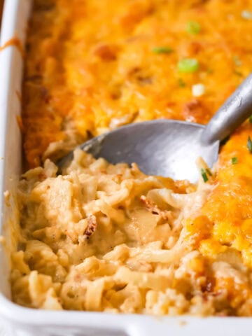 Spoon scooping a serving of hashbrown casserole out of a dish.