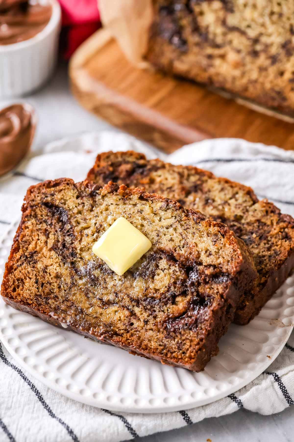 Two slices of nutella banana bread with a pat of butter on top.
