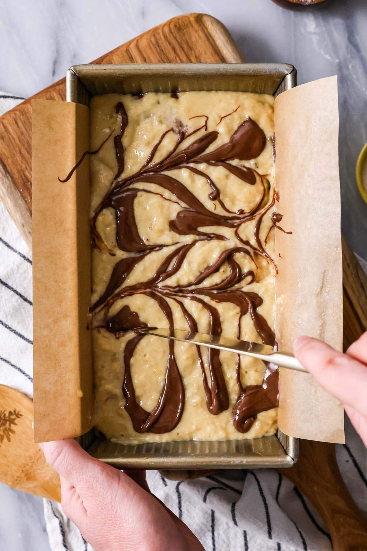 Overhead view of nutella being swirled into banana bread batter.