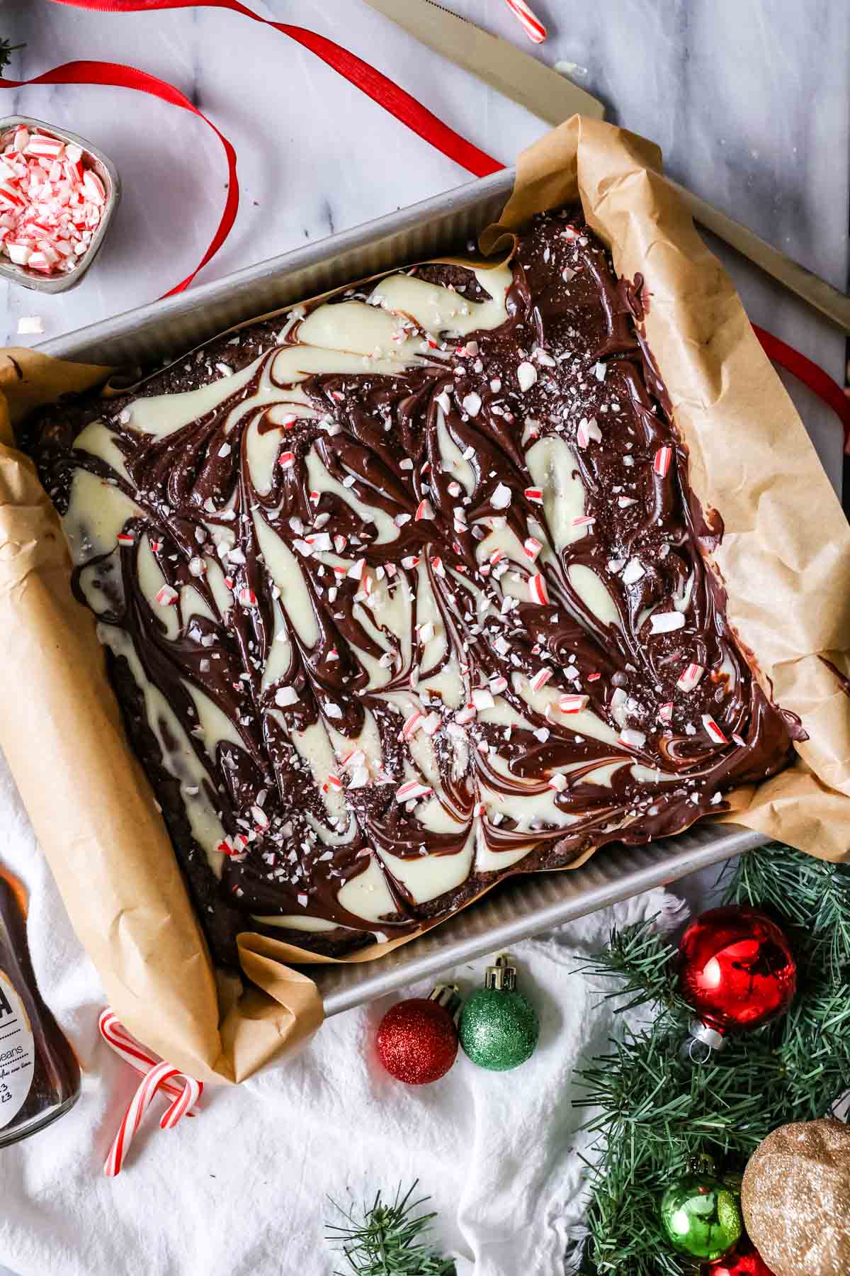 Overhead view of a pan of peppermint bark brownies with a swirled chocolate topping.