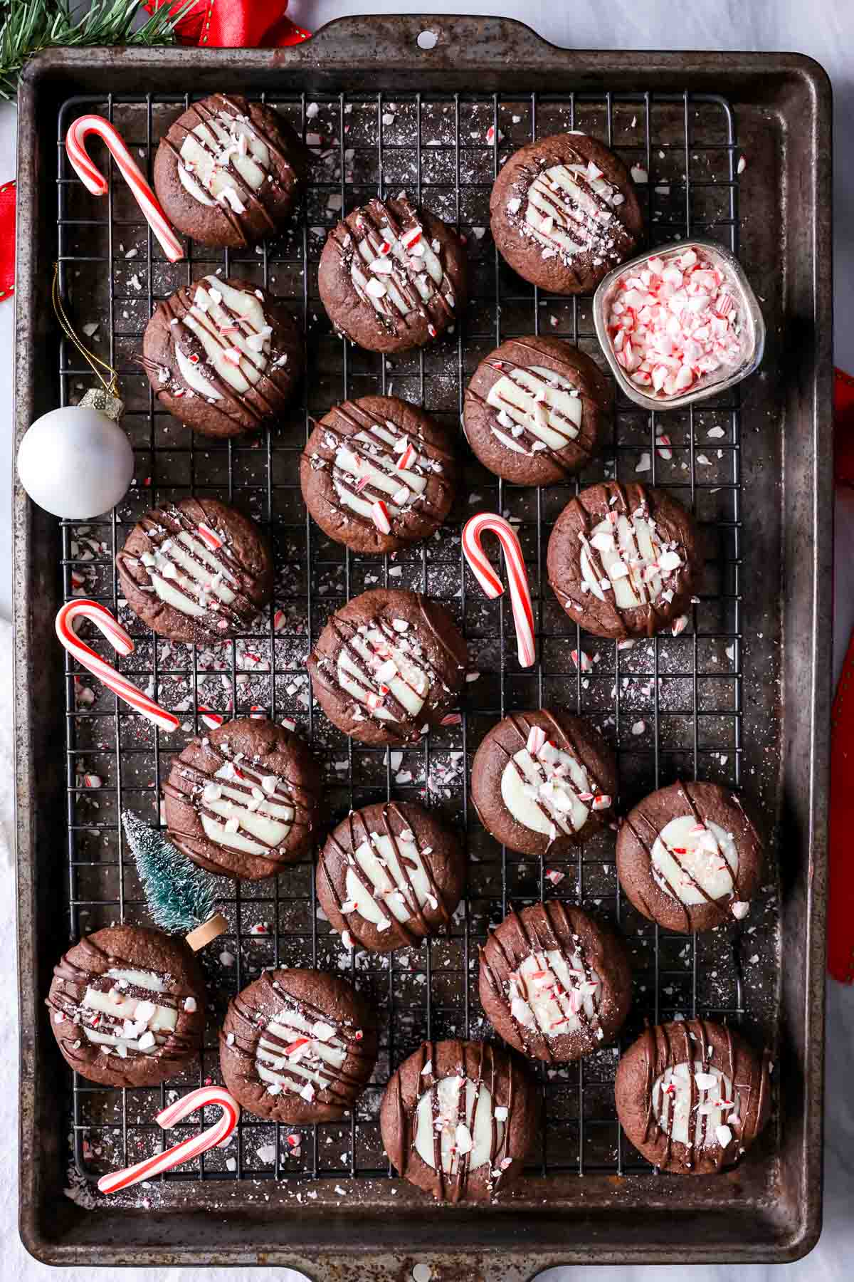 Overhead view of chocolate cookies with white chocolate centers topped with a drizzle of chocolate and crushed candy canes.