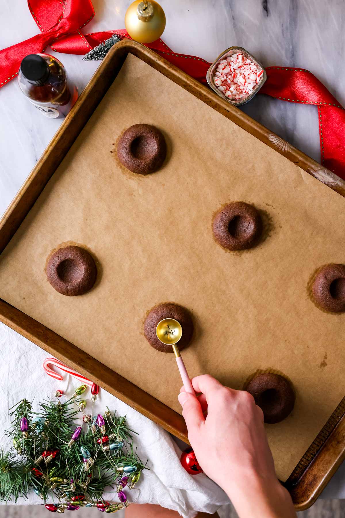 Using a teaspoon to make an indent in the center of chocolate cookies after baking.