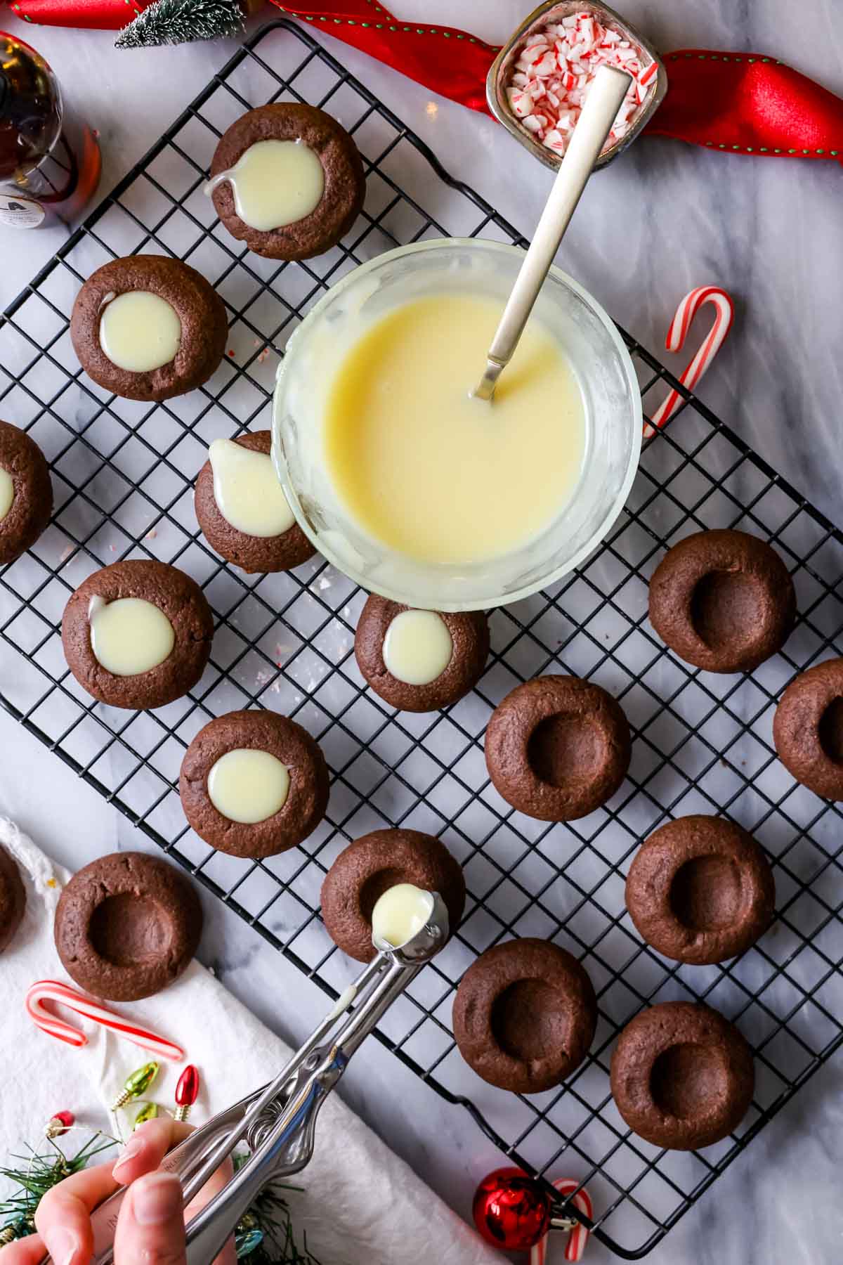 Filling chocolate thumbprint cookies with peppermint white chocolate ganache.