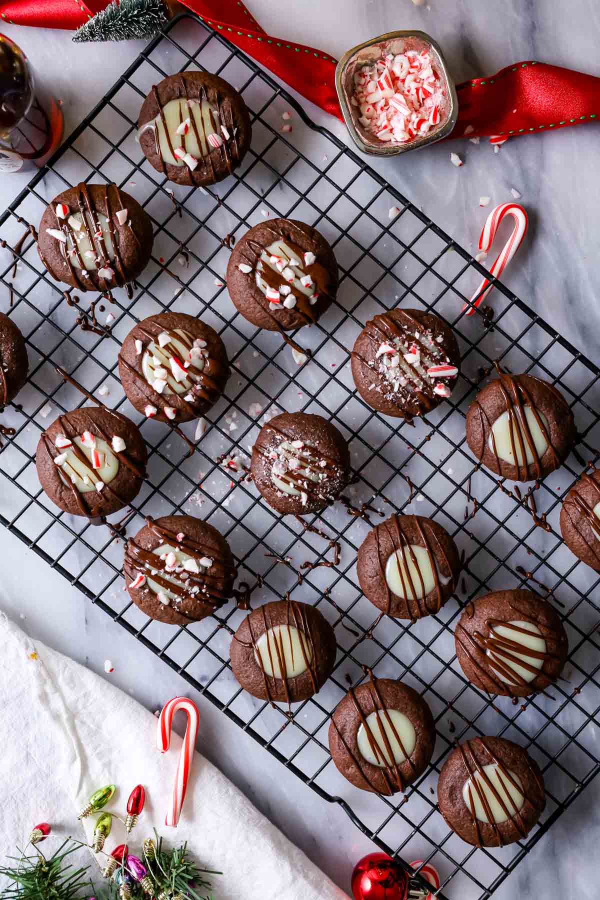 Chocolate cookies that have been filled with white chocolate peppermint ganache, drizzled with dark chocolate, and sprinkled with crushed candy canes.