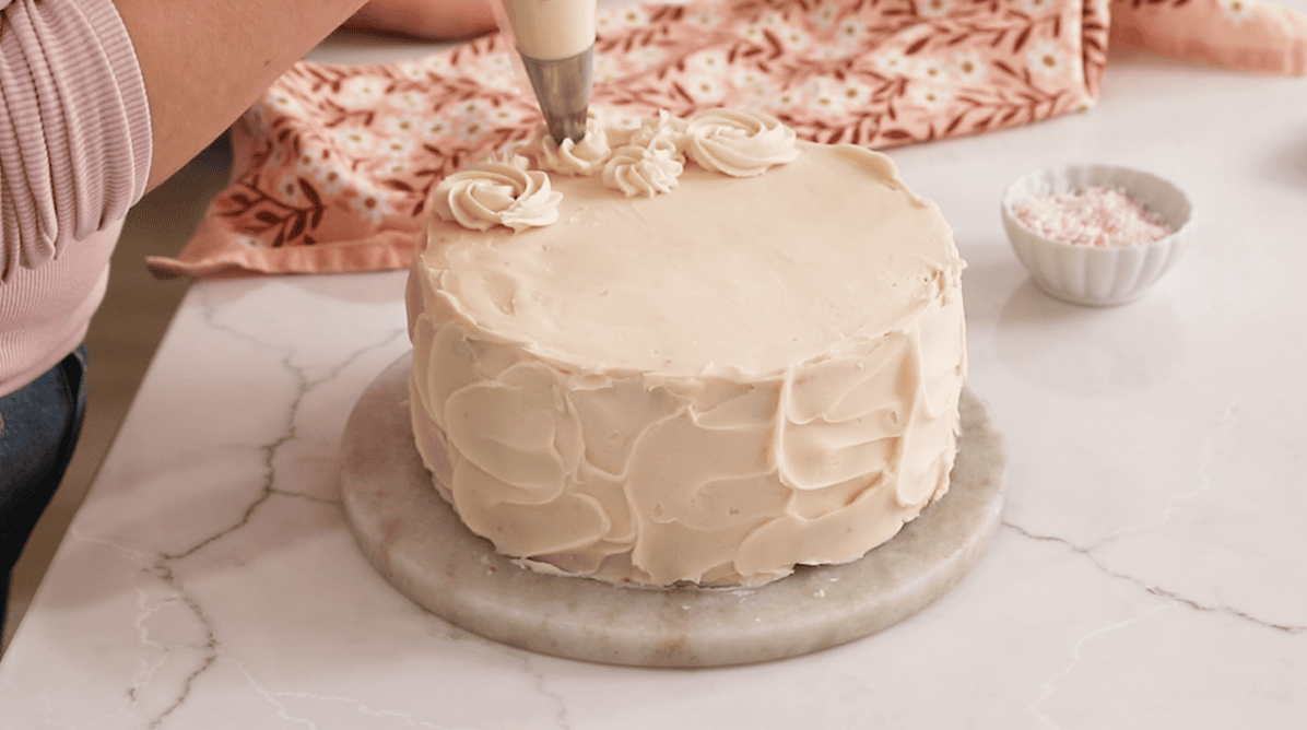 Piping rosettes onto a pink champagne cake.
