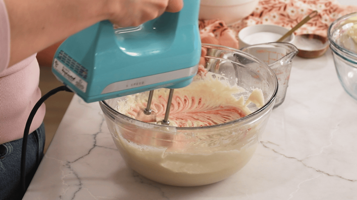 Mixing pink food coloring into cake batter.