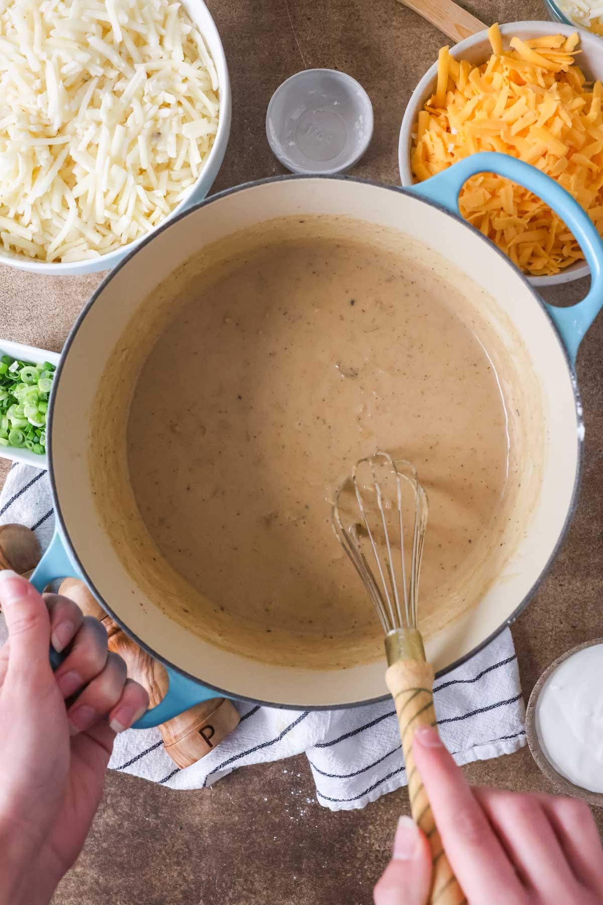 Overhead view of a whisk stirring a roux in a pot.