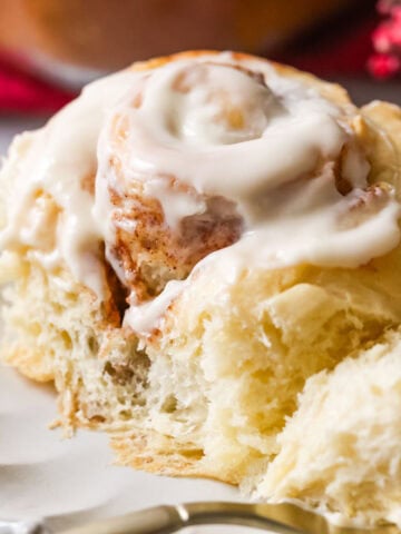 Close up of Amish cinnamon roll that's been cut into with fork showing fluffy, gooey, cinnamon-y interior.