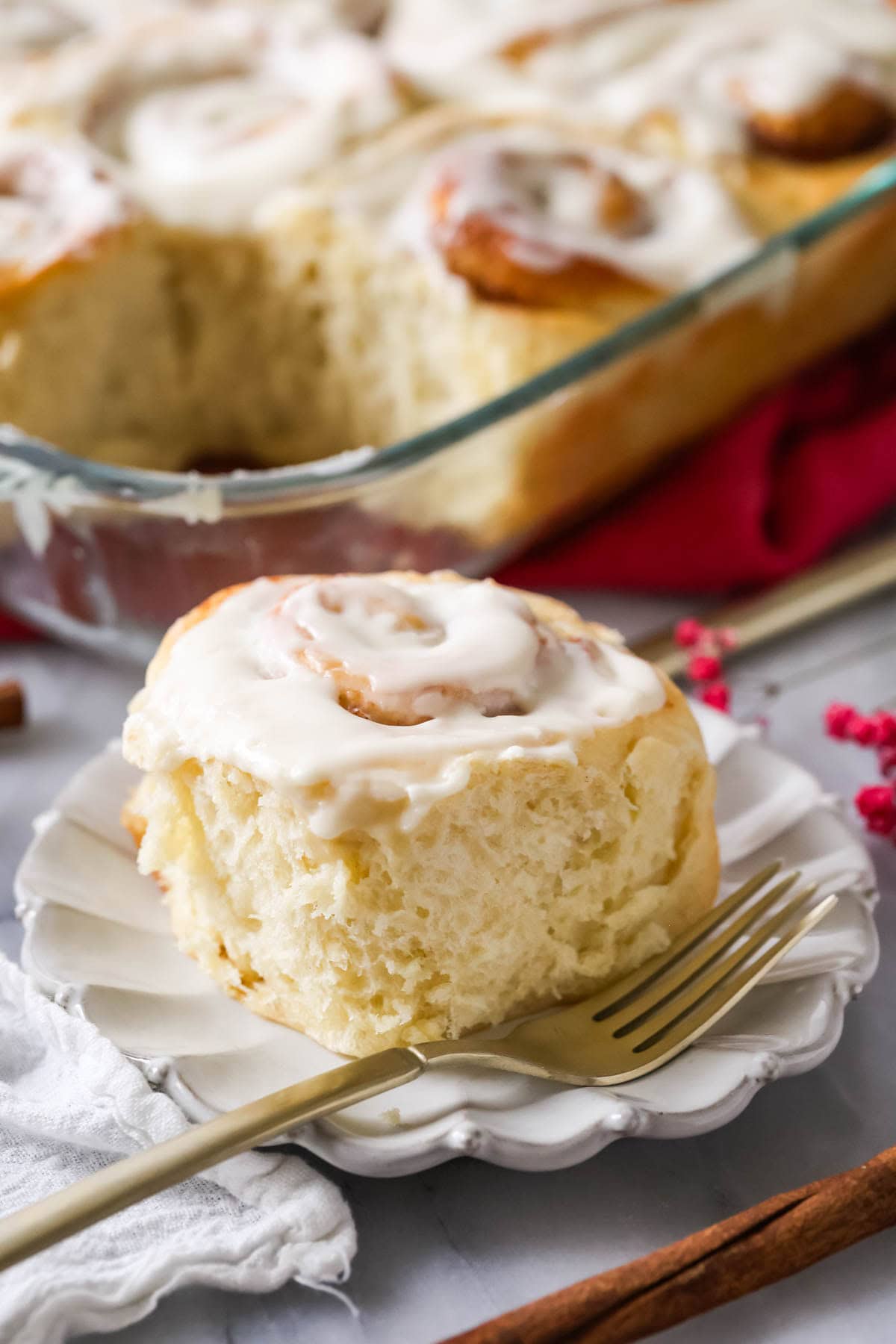 Amish cinnamon roll on white plate with fluffy bite taken out of it.