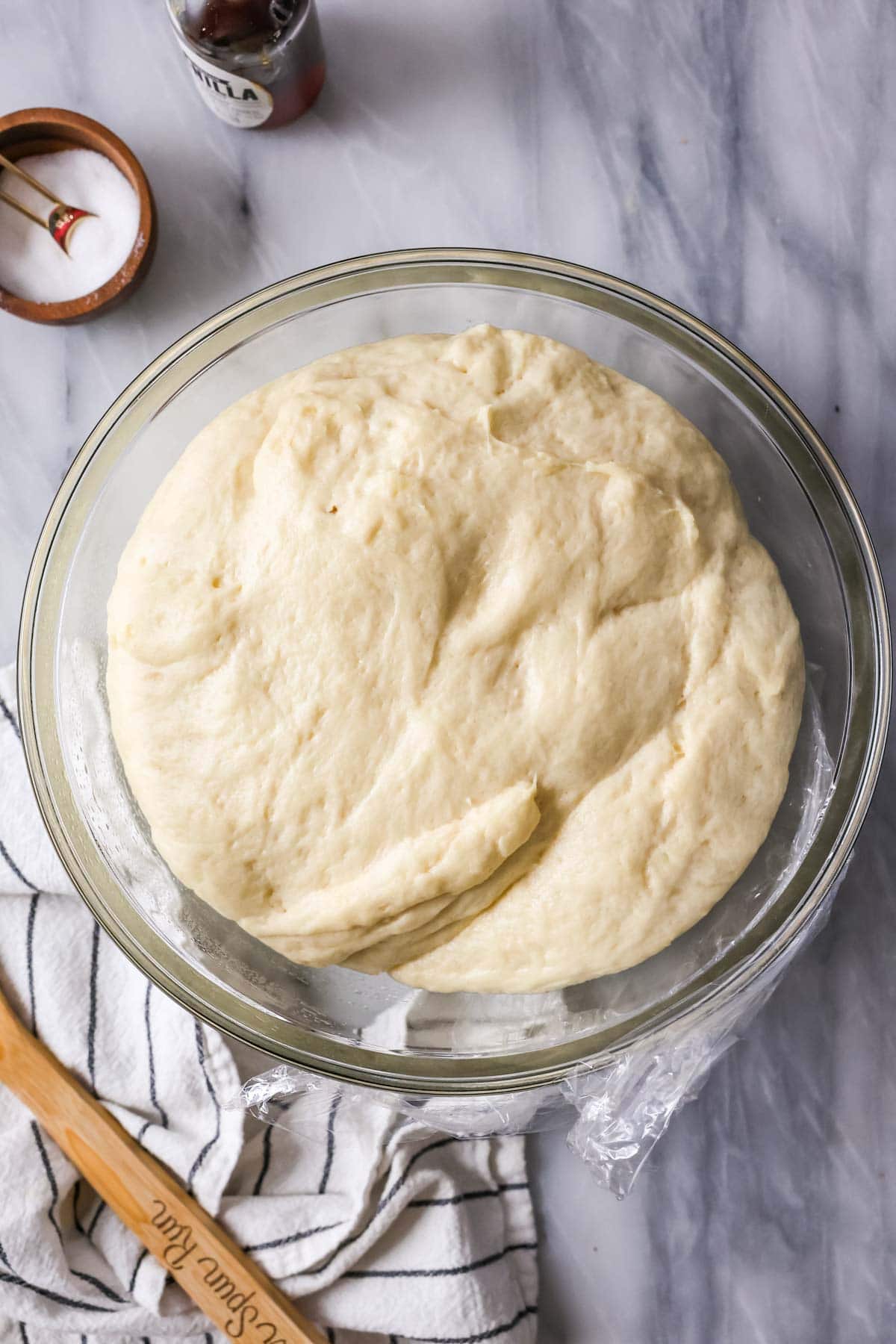 risen cinnamon roll dough in a large glass bowl.