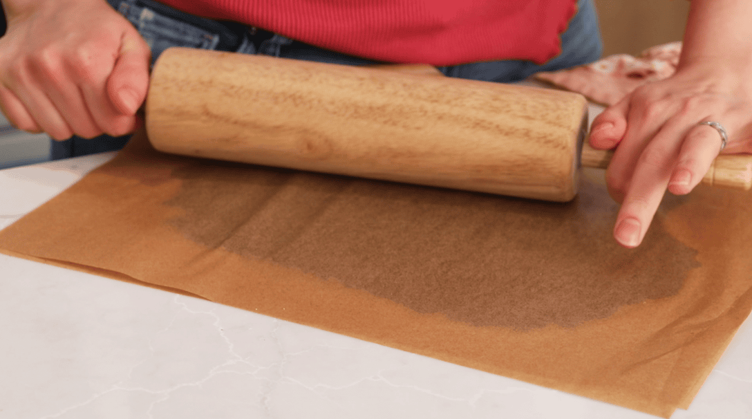 Rolling chocolate craquelin dough between two sheets of parchment.
