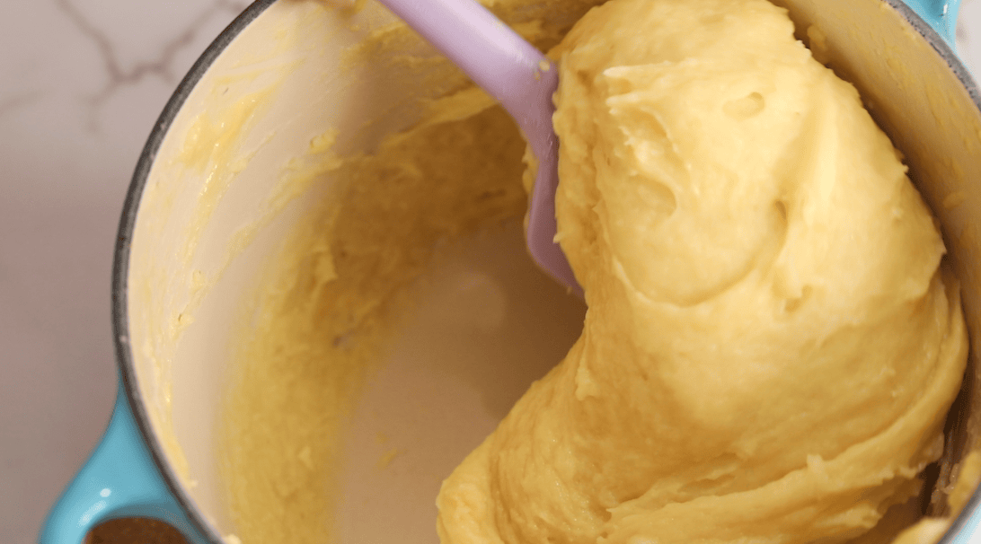 Velvety choux dough in a pot after adding the eggs.