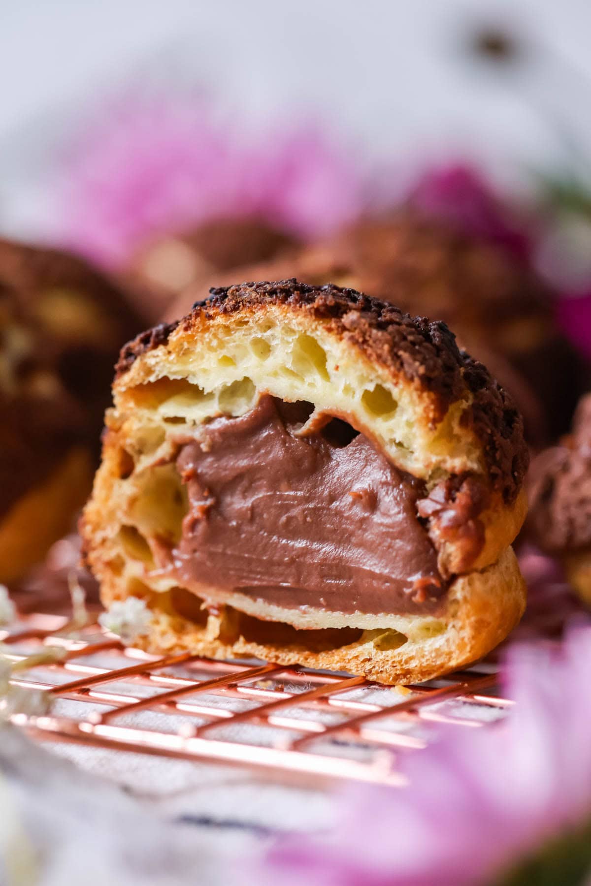 Close-up view of a choux bun filled with chocolate pastry cream and topped with chocolate craquelin.