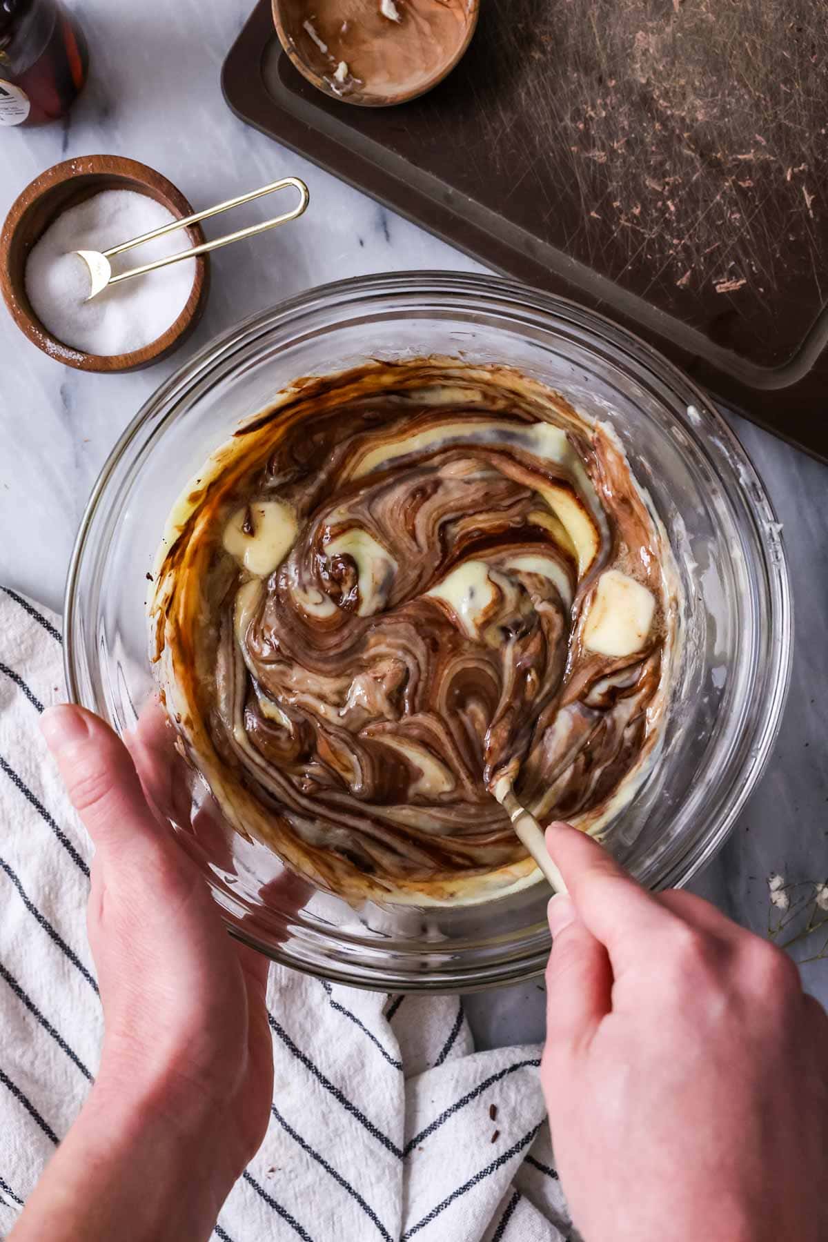 Overhead view of chocolate and butter being whisked into pastry cream.