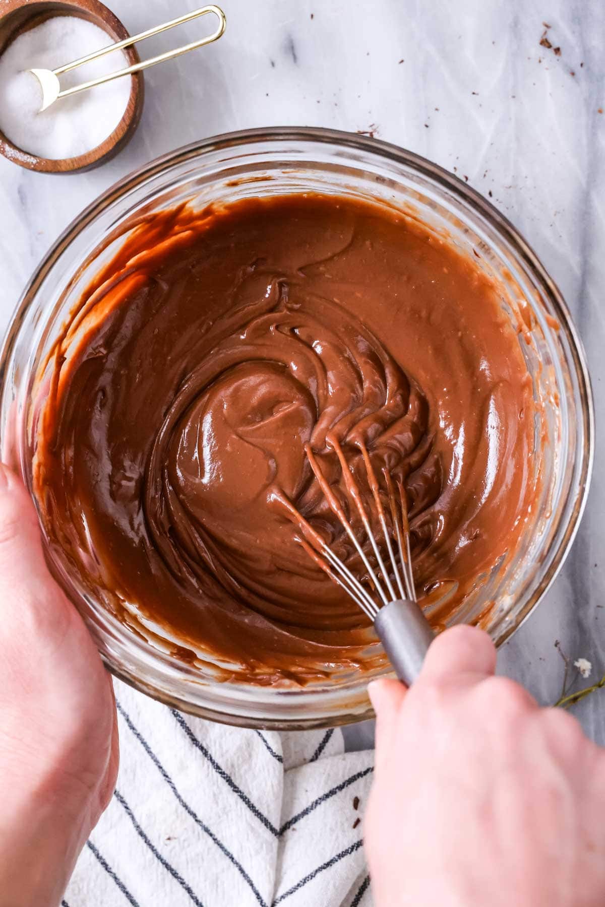 Overhead view of a bowl of chocolate pastry cream being whisked.
