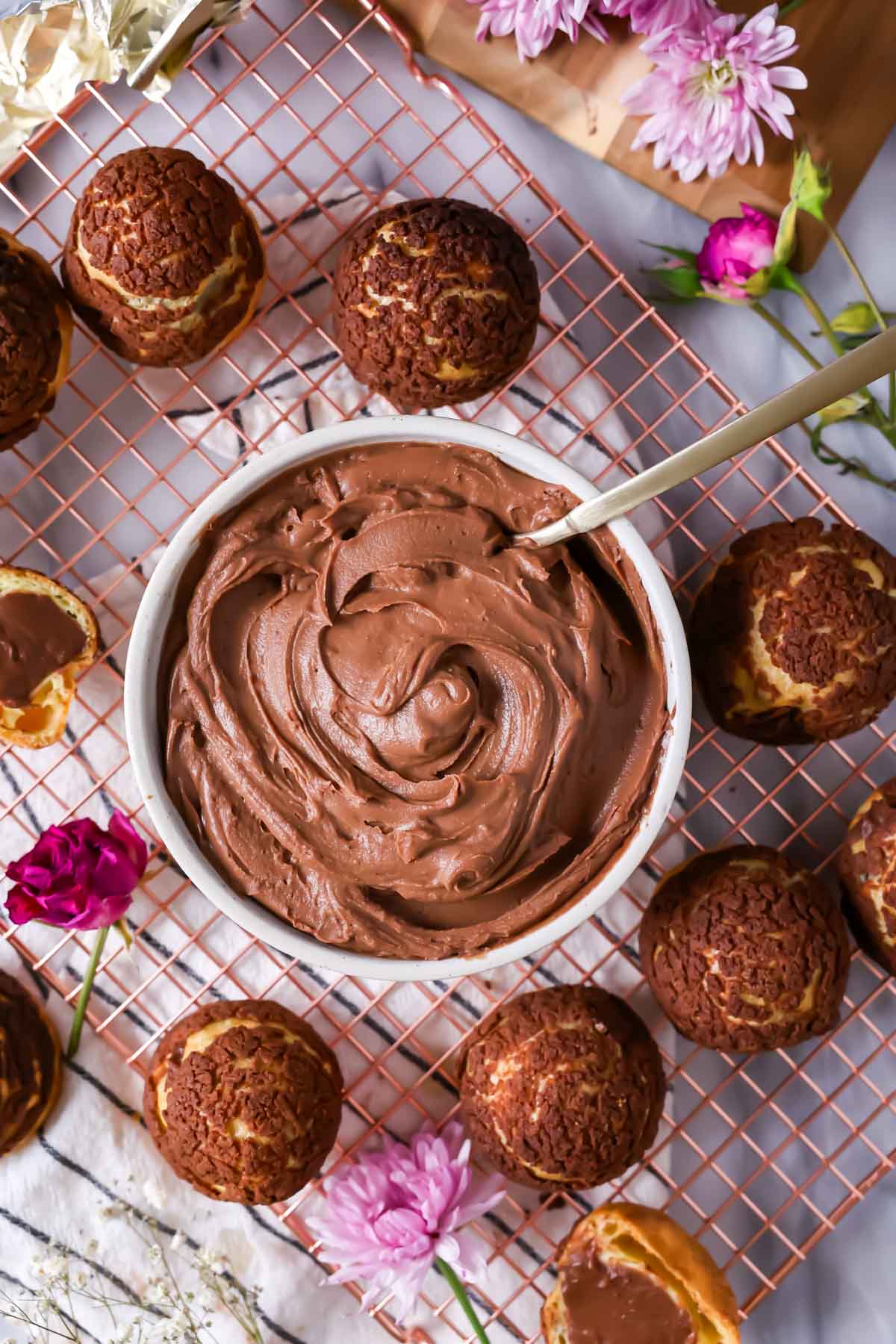 Overhead view of a bowl of chocolate pastry cream surrounded by chocolate choux au craquelin.