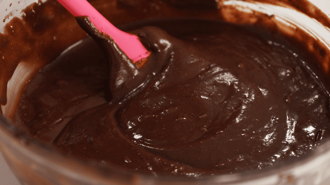 Close-up view of chocolate cake batter being stirred with a spatula.