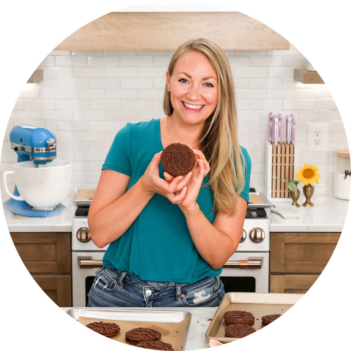 The author (Sam) in blue shirt holding Fudge round cookie with blue mixer in background