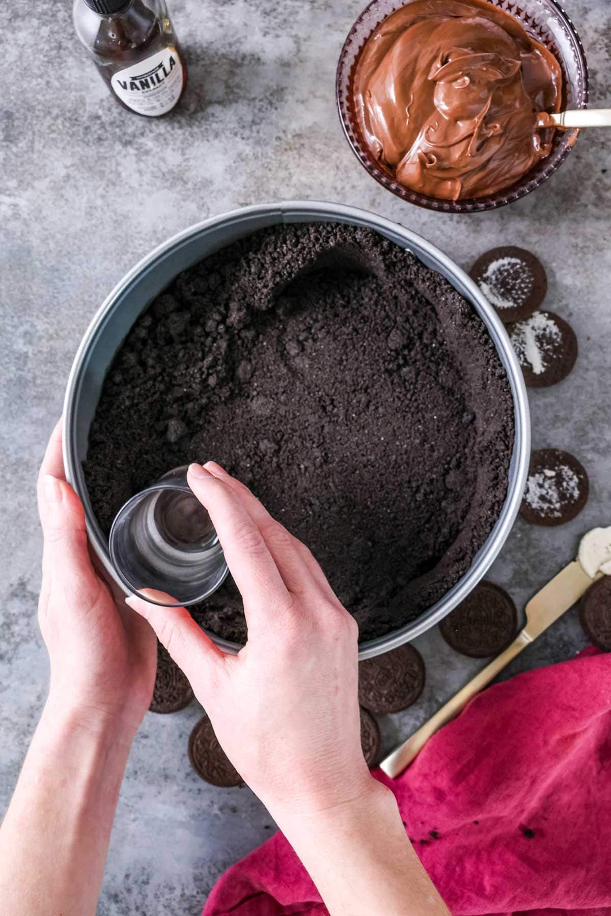 Overhead view of an Oreo crust being pressed into a springform pan.