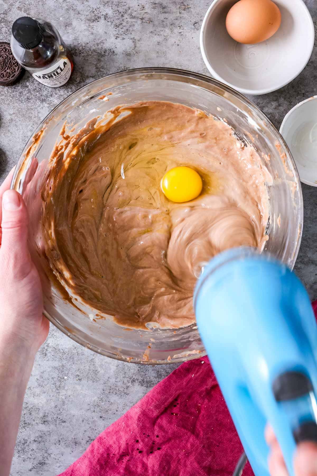Overhead view of eggs being stirred into a Nutella cheesecake batter.
