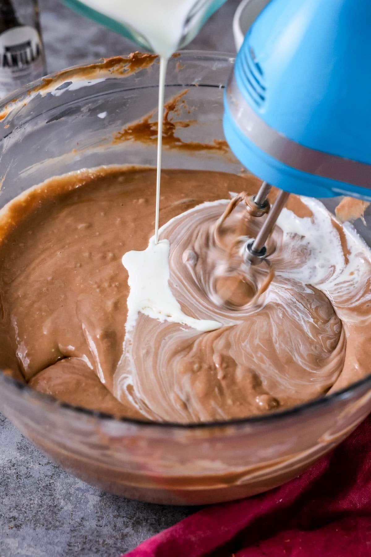 Cream being drizzled into a cheesecake batter.
