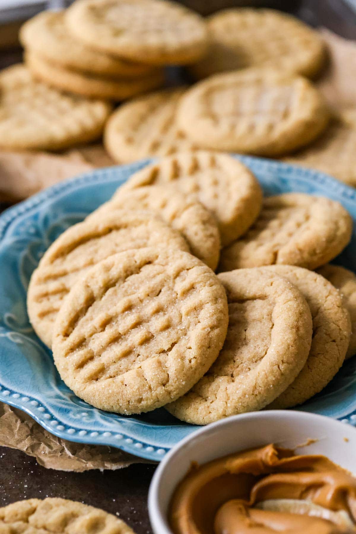 Plate of peanut butter cookies with more cookies in the background.