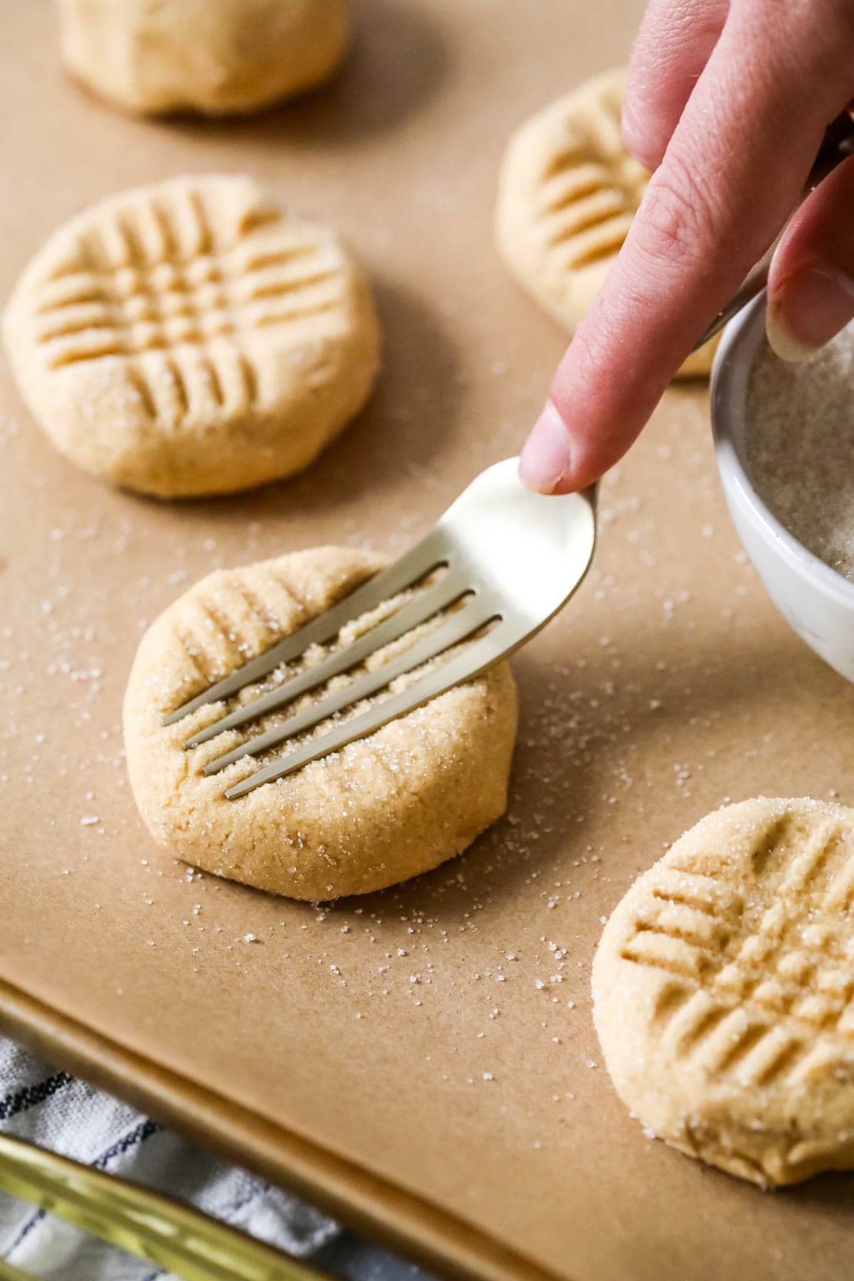 Using a fork to make a crisscross pattern in peanut butter cookies.