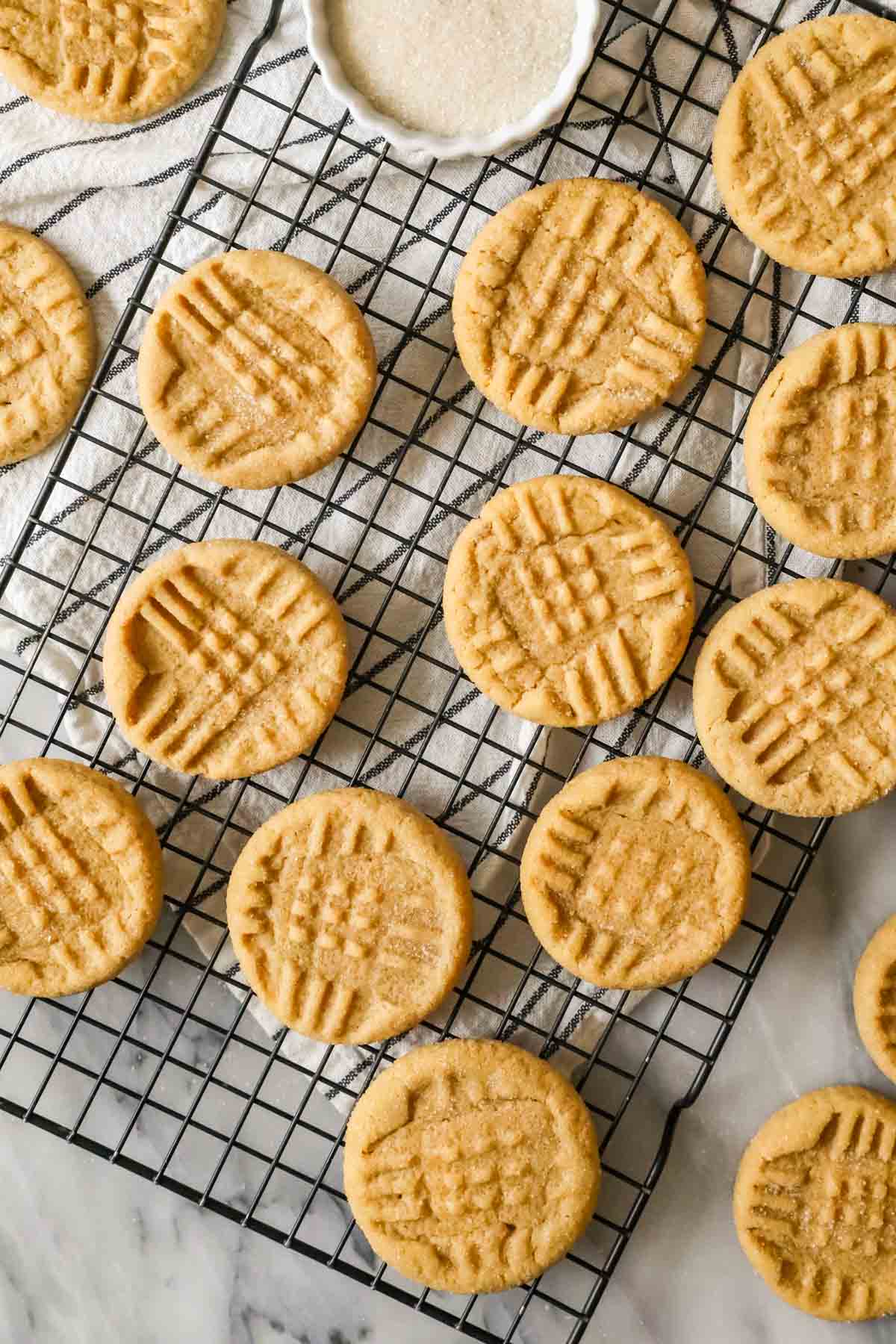 Overhead view of peanut butter cookies on a cooling rack after baking.