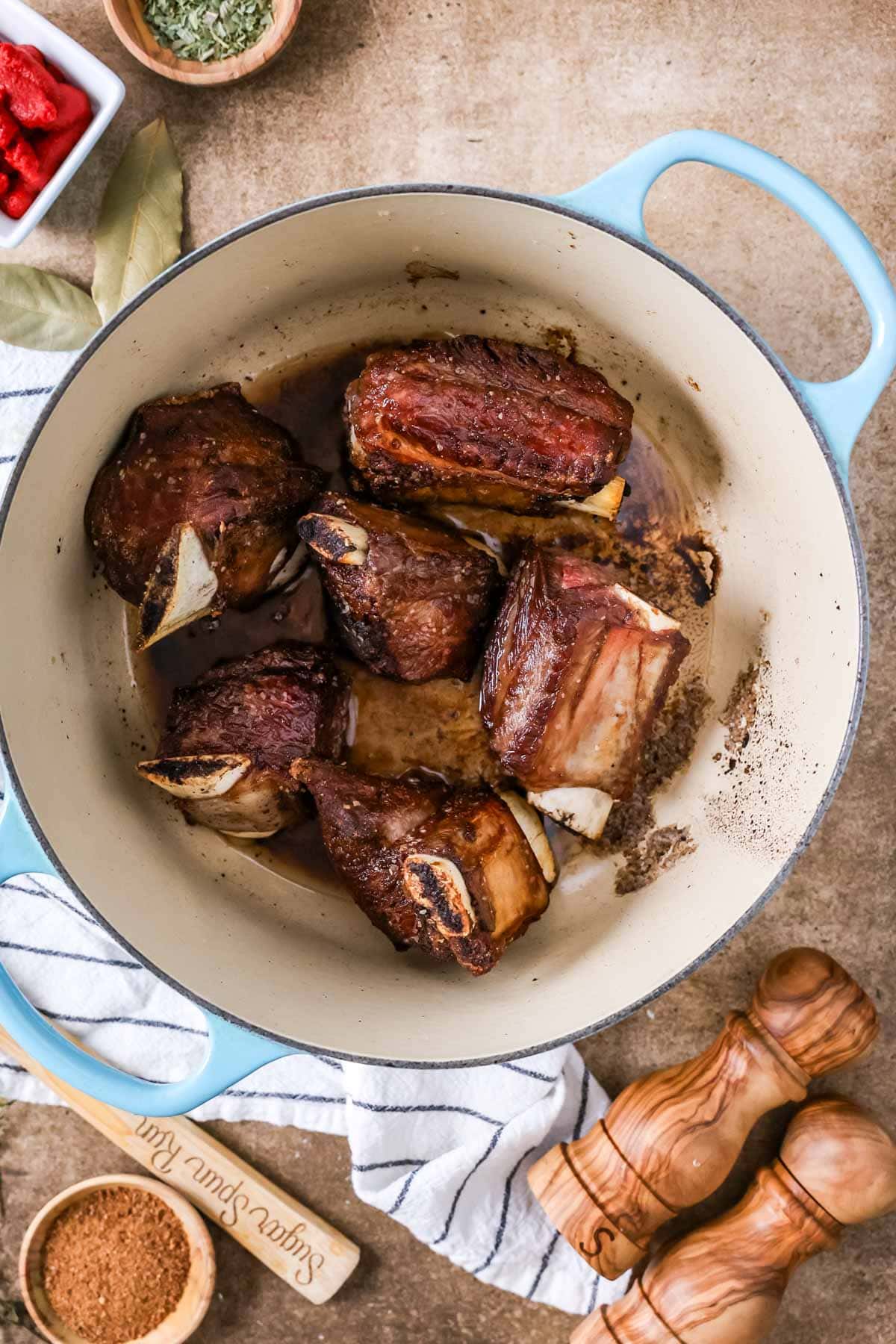 Overhead view of short ribs searing in a dutch oven.