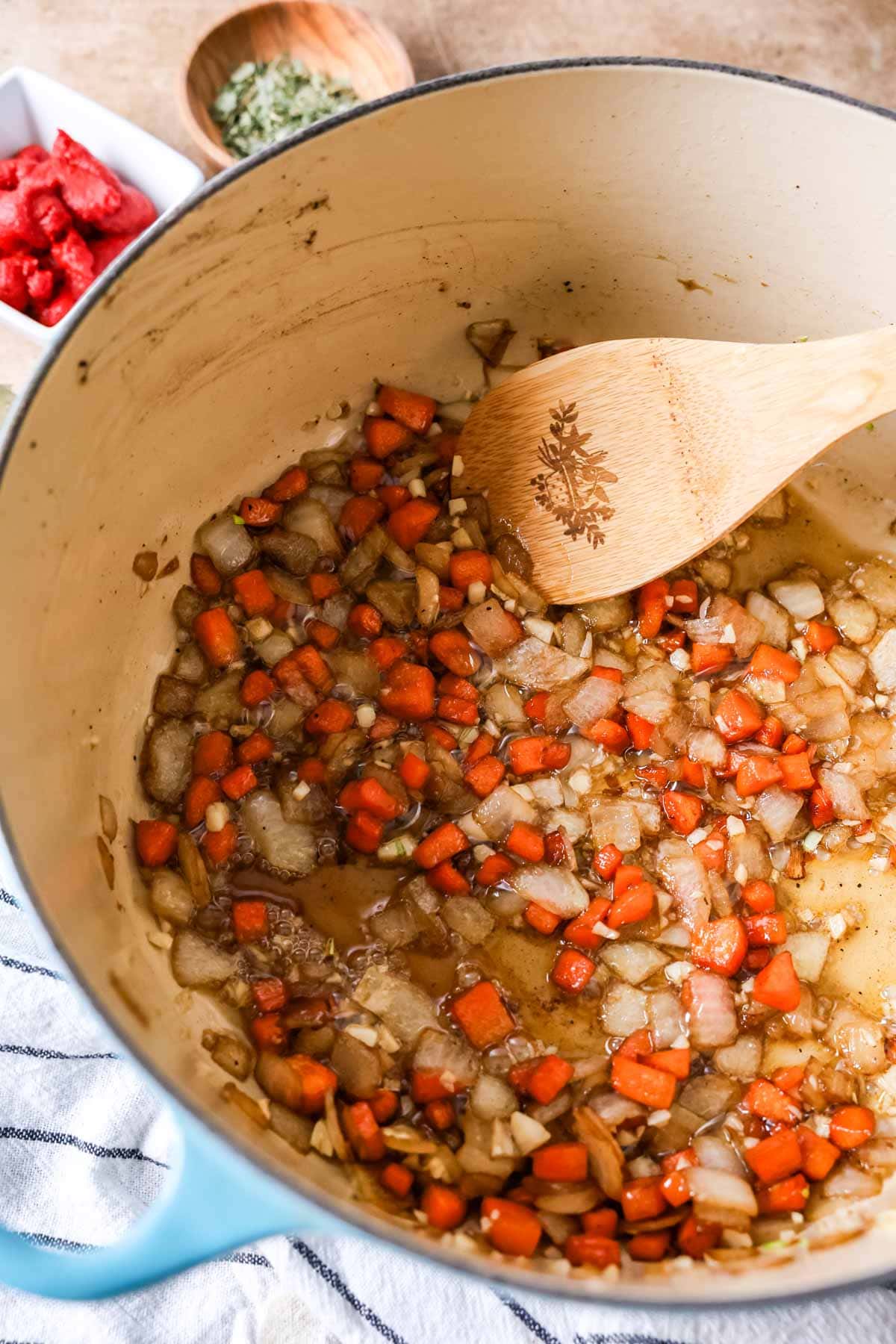 Overhead view of diced carrots and onions searing in a pot.