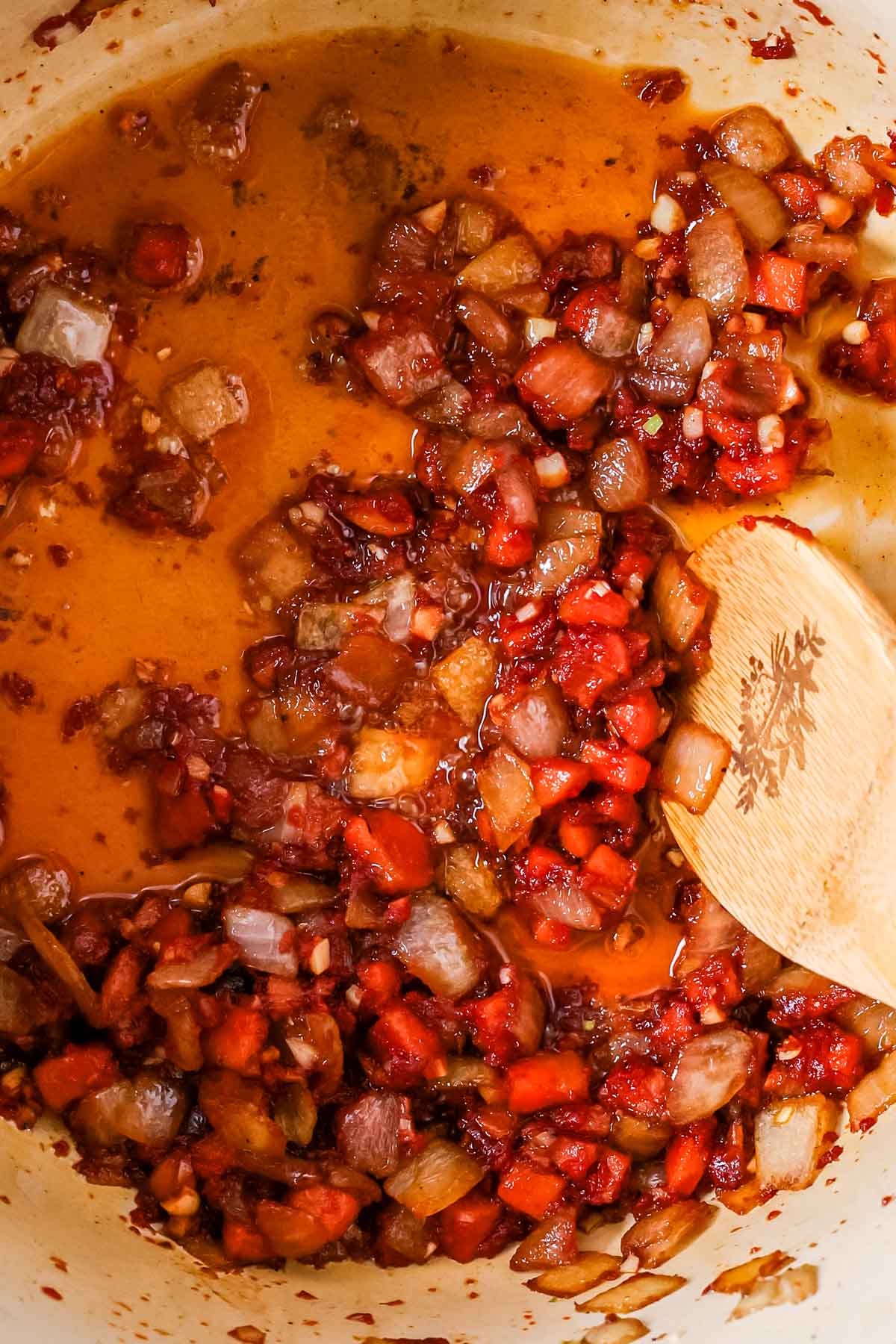 Close-up view of carrots and onions cooking in caramelized tomato paste.