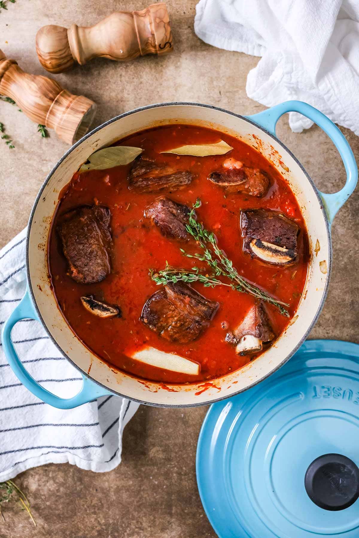Overhead view of a dutch oven with short ribs in a tomato based braising liquid.