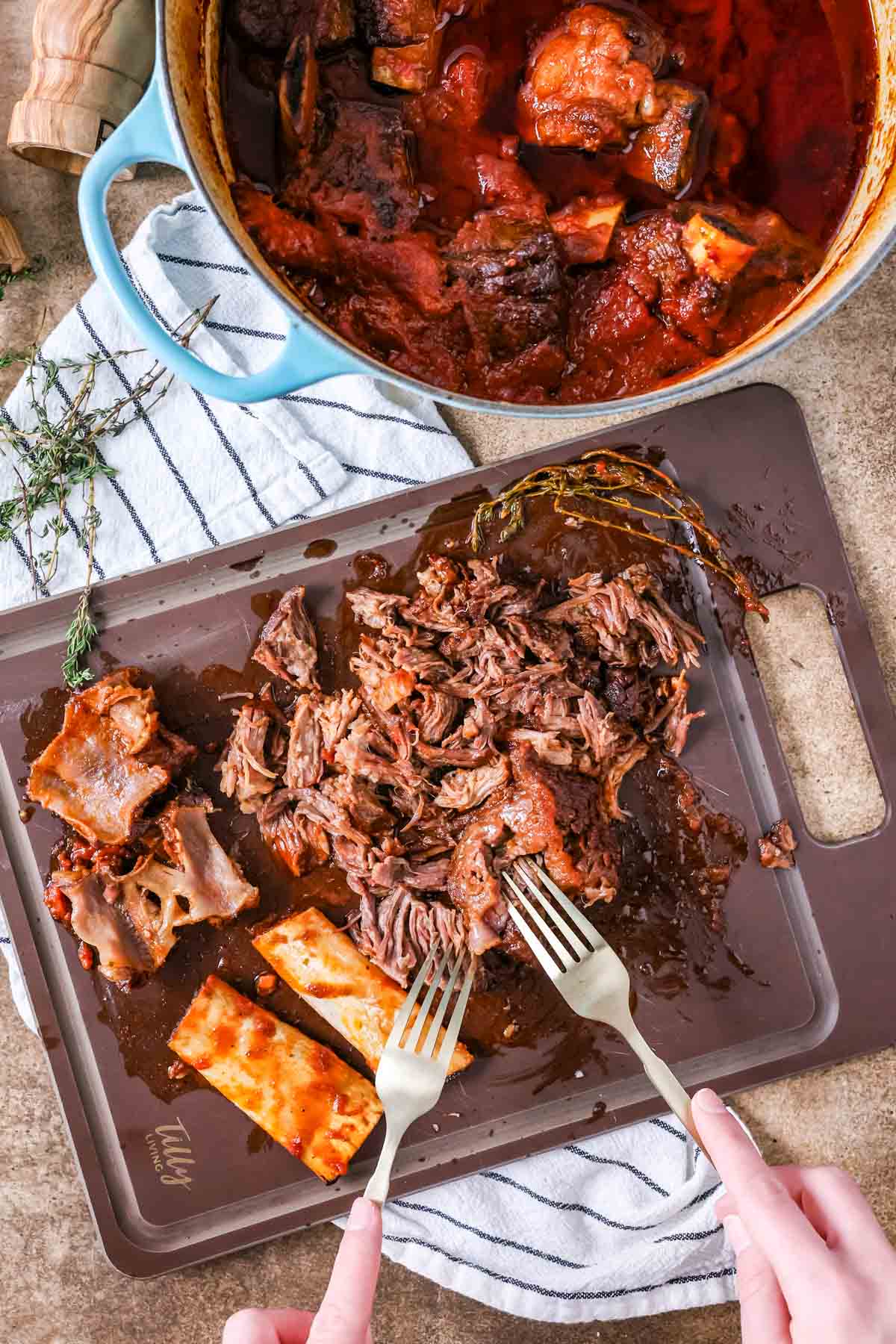 Forks shredding meat off spare ribs.
