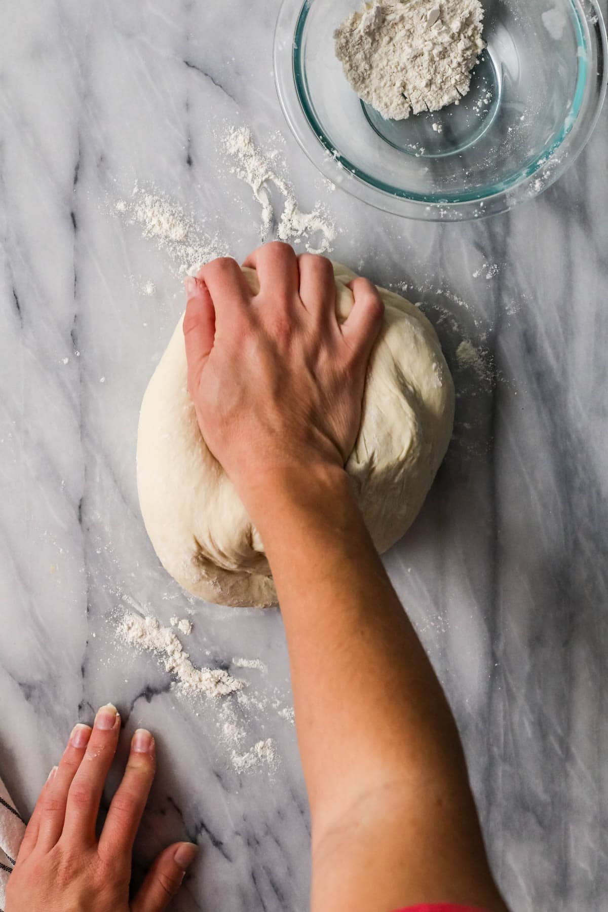Hands kneading dough into a smooth ball.