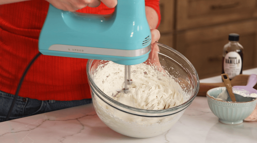 Whipping mascarpone frosting to stiff peaks.