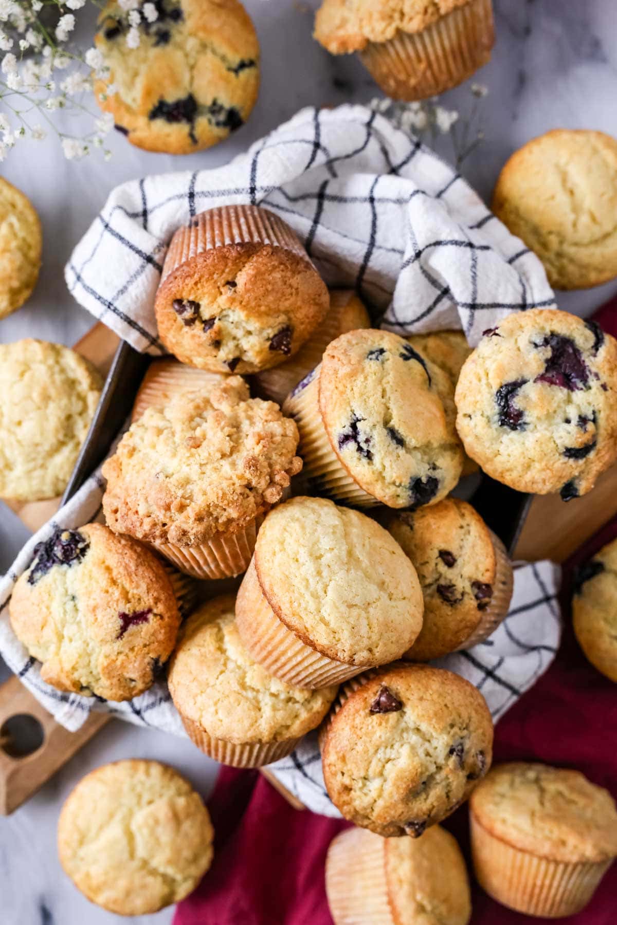 Overhead view of a towel-lined pan of muffins of varying flavors.