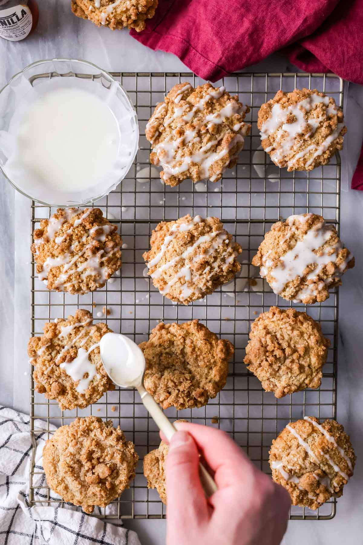 Glaze being drizzled over streusel topped muffins.