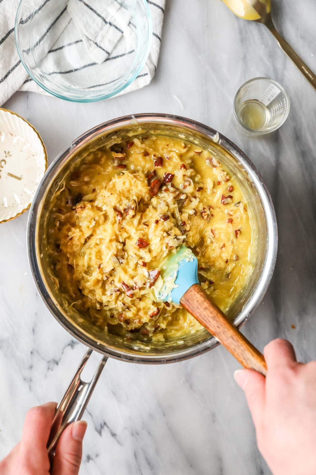 Coconut and pecans being stirred into a caramel.