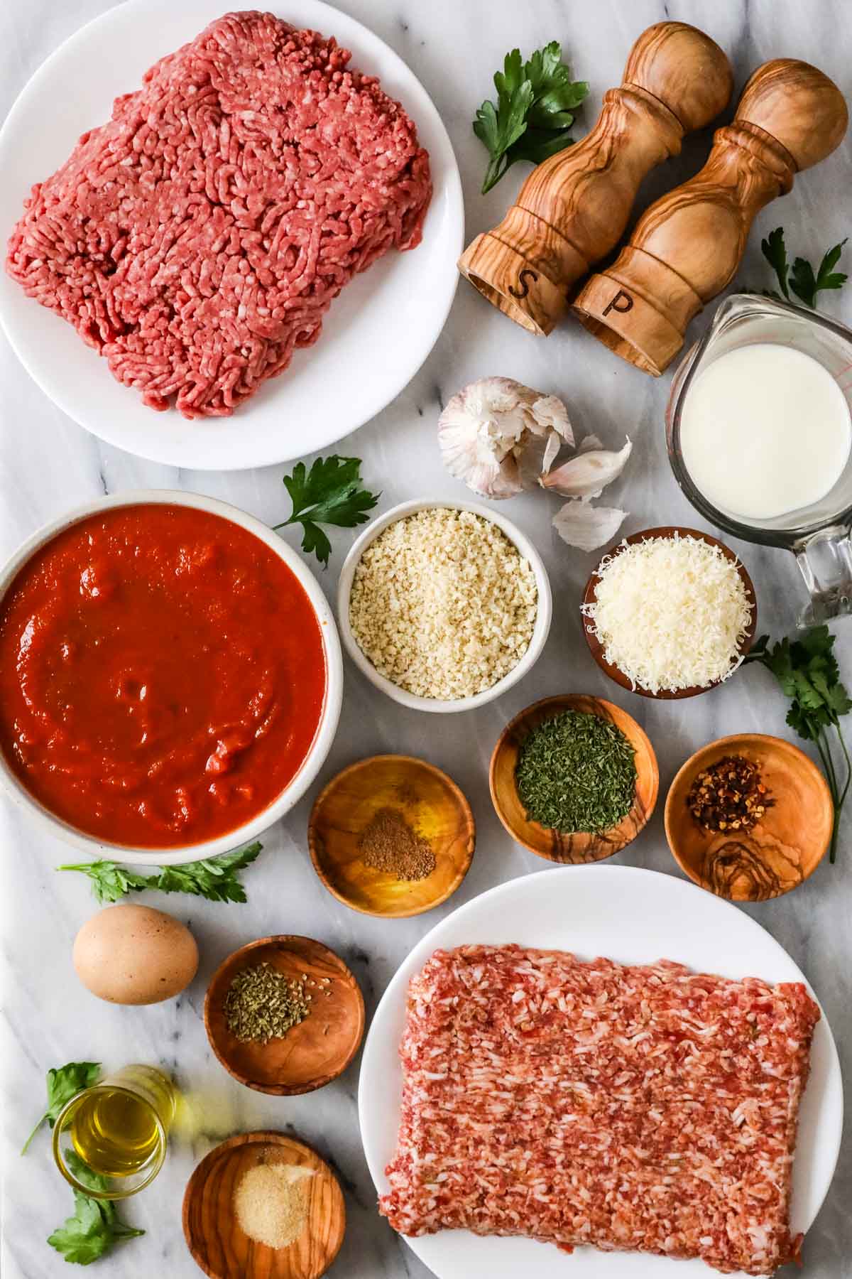 Overhead view of ingredients including ground beef, ground sausage, milk, panko breadcrumbs, and more.