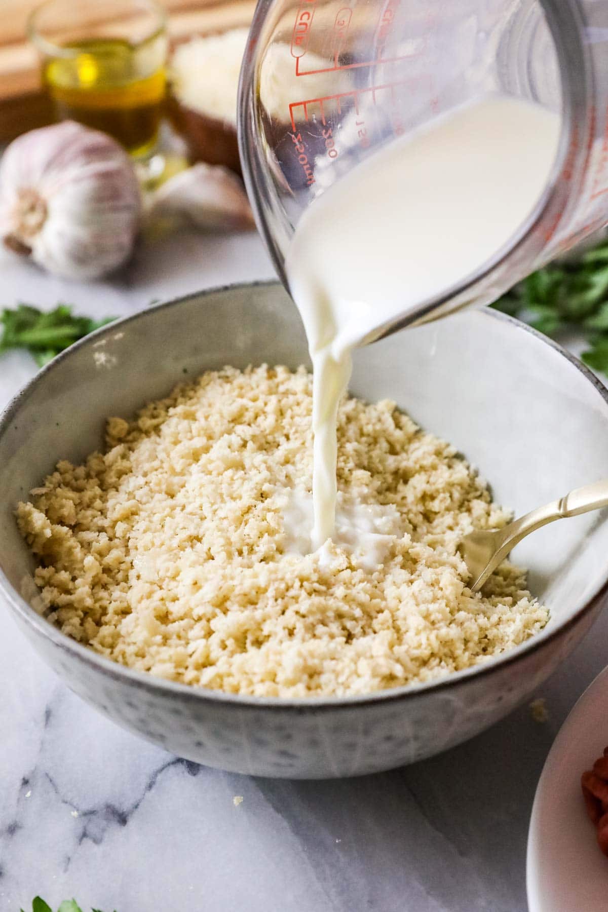Pouring milk into breadcrumbs to make a panade.