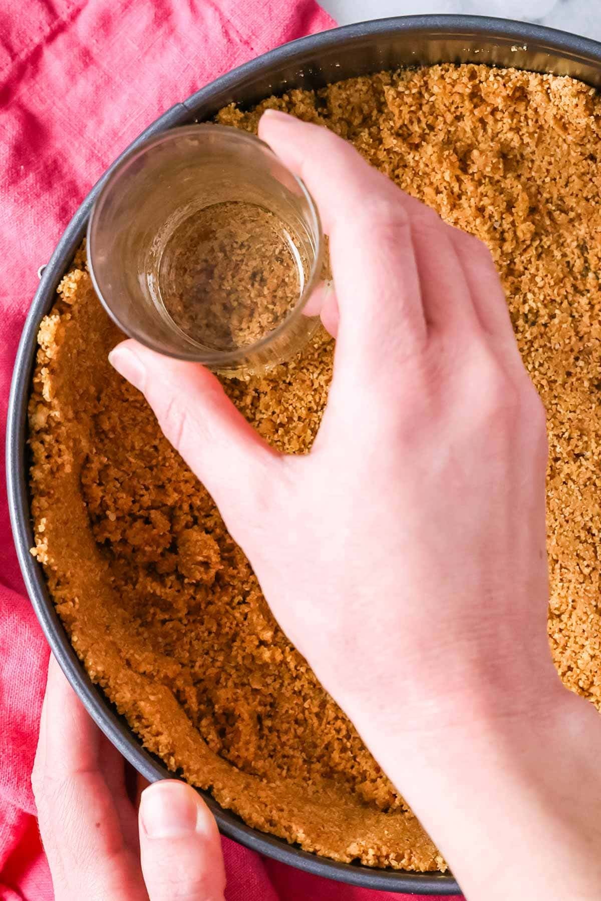 Pressing a graham cracker crust into a springform pan.