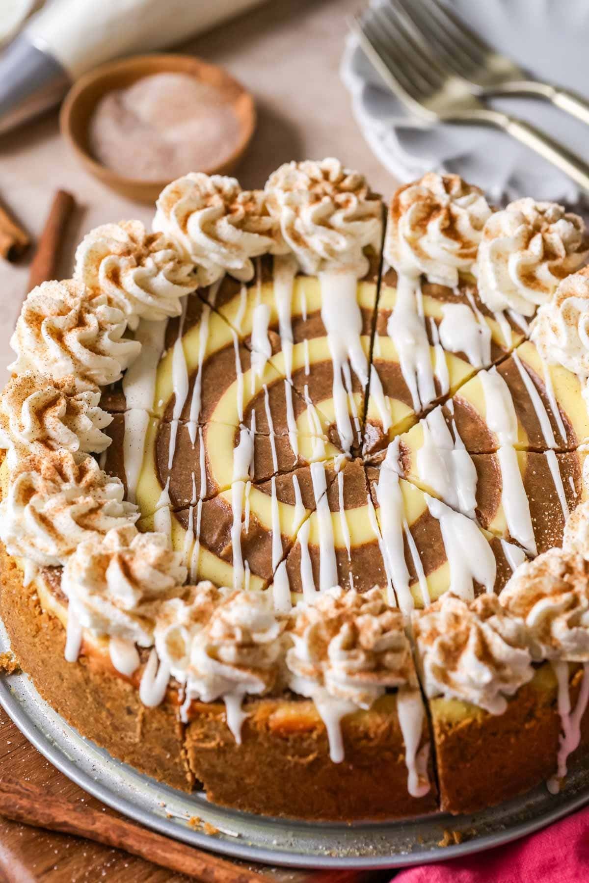 Close-up of a cinnamon roll cheesecake that has been cut into 9 slices.