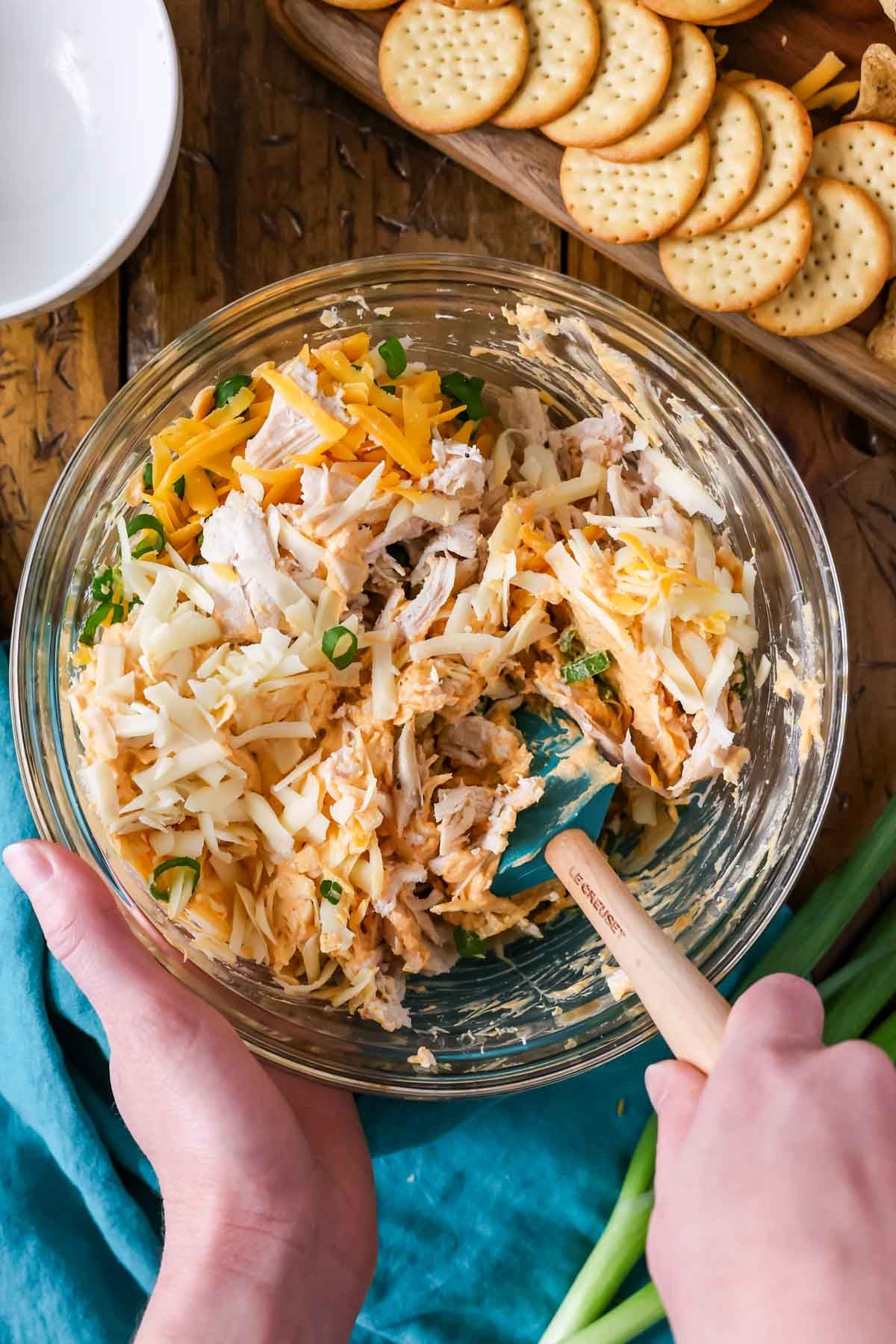 How to make buffalo chicken dip -- mixing ingredients together in glass mixing bowl.
