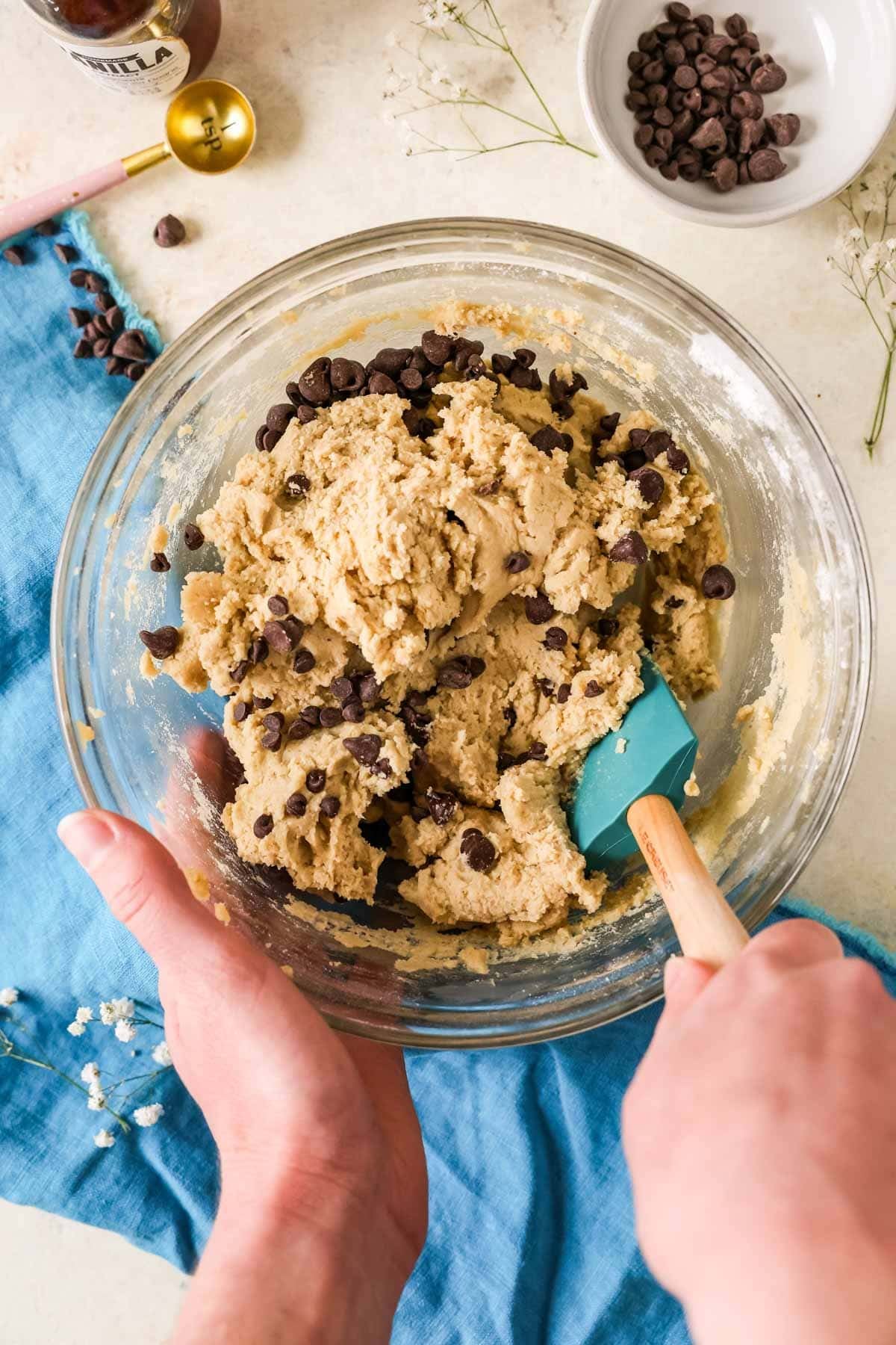 Overhead view of bowl of edible cookie dough -- chocolate chips being mixed in.