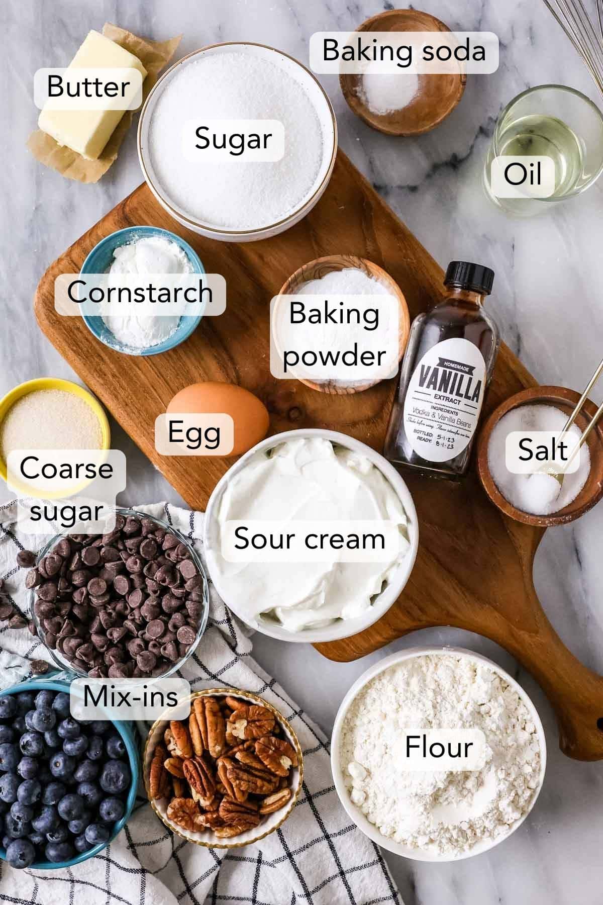 Overhead view of ingredients including sour cream, flour, chocolate chips, blueberries, and more.